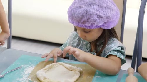 Pretty 5Year Old Girl in Cap Making Bumpers of Raw Dough for Baking at the Master Class