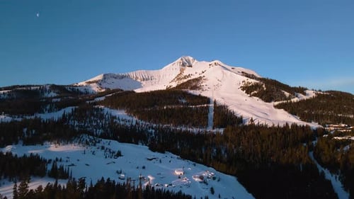 A drone shot of snowy Big Sky, Montana in winter, showcasing the ski resort and majestic mountain te
