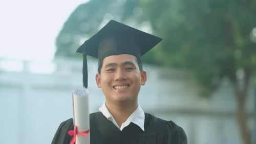 Proud Male Graduate Holding Diploma and Smiling at Camera