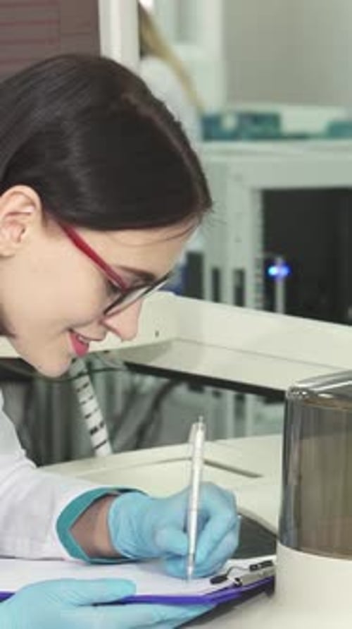 Scientist Writing on Clipboard in Medical Laboratory