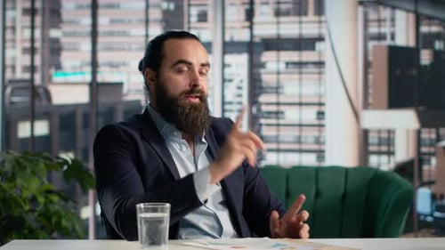 Business Man Gesturing While Sitting in Office