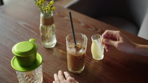 Persona que agrega leche condensada al café helado en un café