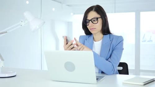 Using Smartphone Young Businesswoman Browsing Online at Work