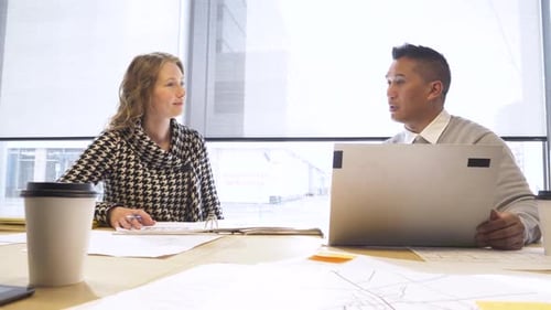 Business People With Paperwork And Laptop Talking In Office Meeting