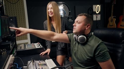 a girl singer and a male sound engineer work together in recording studio to create a new song