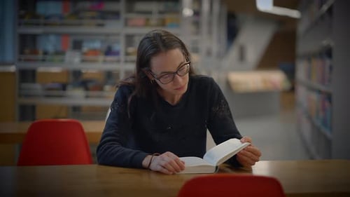 A Committed and Focused Reader Engaged in a Modern Library Setting Surrounded By Books