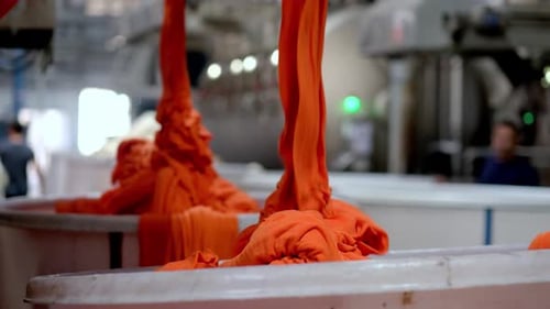 Bright Orange Textile Strands Poured into Industrial Container