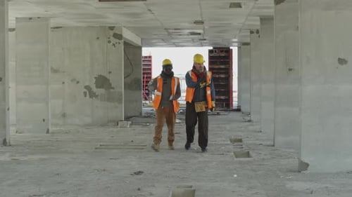 Diverse Engineers Walking along Concrete Building under Construction