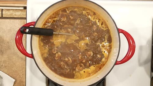 Wild rice mushroom soup in a rich broth boiling on the stove - overhead view in slow motion WILD RIC