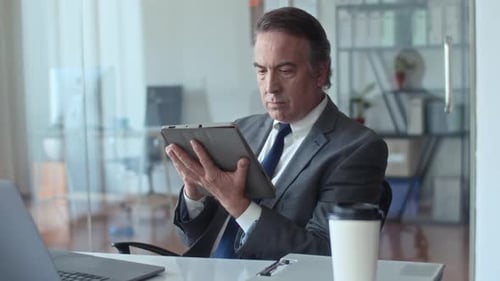 Male Mature Entrepreneur Working on Digital Tablet at Office