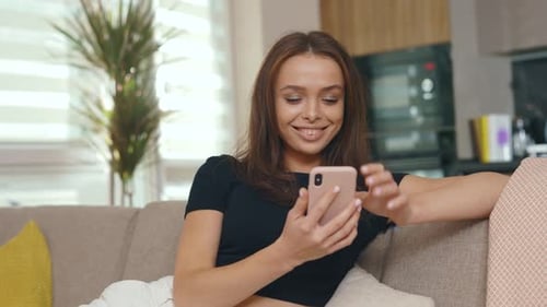 Smiling woman using cellphone on couch in living room