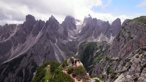 Aerial view of couple hiker at a viewpoint in Dolomites mountain peak
