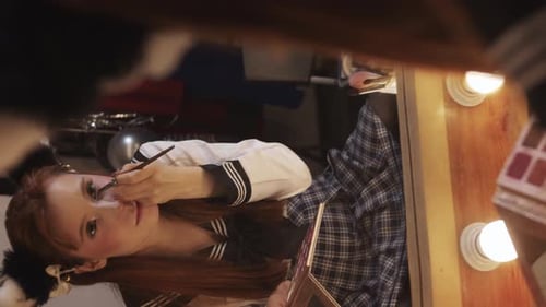 Woman Applying Makeup at Lighted Vanity Mirror