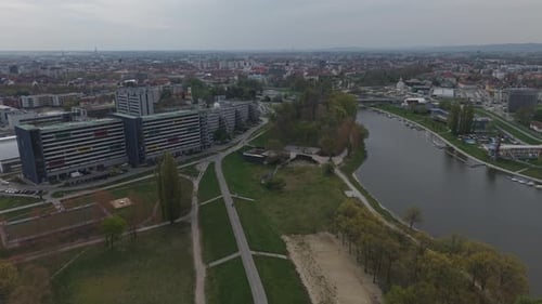 Aerial view of a modern city with a river flowing through green park areas and residential
