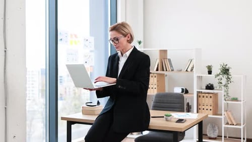 Professional Woman Working on Laptop in Modern Office Setting
