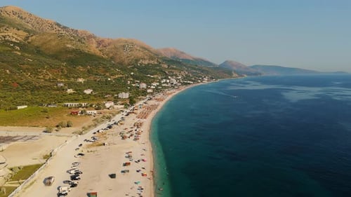 A stunning coastline with turquoise waters and scattered beachgoers on a sunny day , aerial view