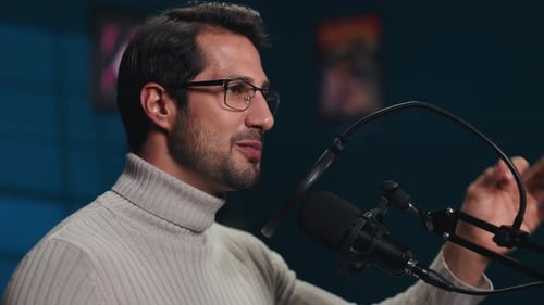 Portrait of Man Host in Turtleneck Sweater Talks in Mic on Podcast in Studio
