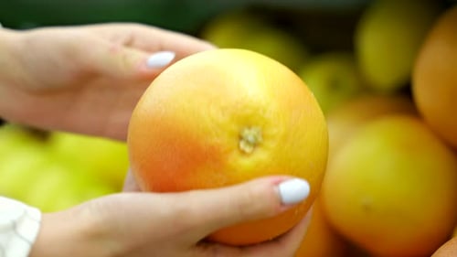 Closeup of a Young Girl in a Supermarket Choosing Oranges on a Fruit Counter