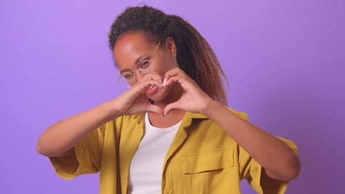 Young Friendly African American Woman with Smile Makes Heart Shape From Fingers