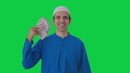 Happy Muslim man using money as fan Green screen