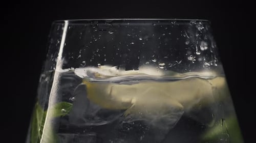 Refreshing Drink: Lemon Slice Plunges into Icy Beverage