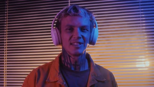 Man with Headphones Smiling in Neon Room