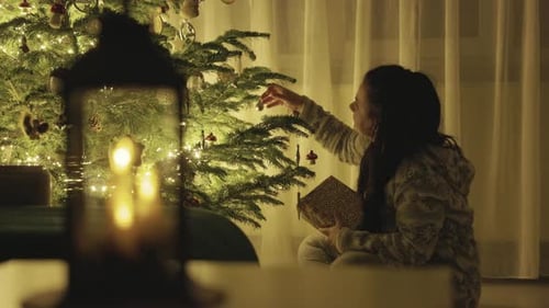 Woman Decorates Christmas Tree at Home with Gifts