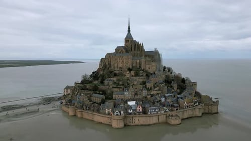 Drone orbiting around Mont Saint Michel on cloudy day, Normandy in France. Aerial circling