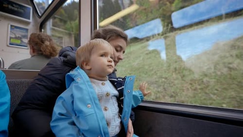 Madre sostiene a su hijo pequeño en brazos en el asiento del tren de pasajeros
