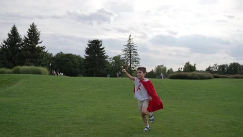 Boy in a Red Cape Running Through Meadow
