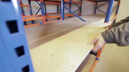 Worker Installing Wooden Shelf on Metal Rack