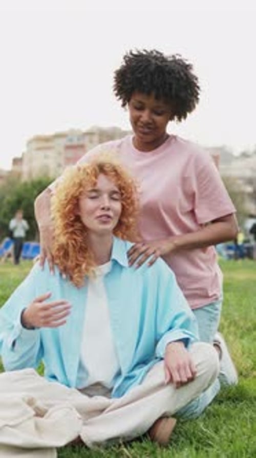 Young Woman Receiving Relaxing Shoulder Massage From Friend in Park