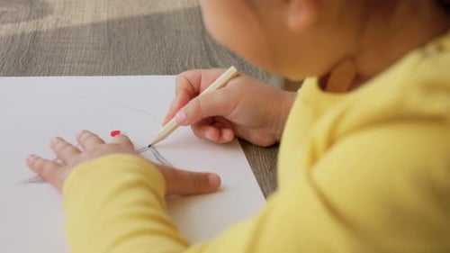 Child Drawing With Pencil on Paper Indoors