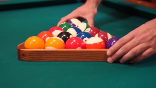 Person Racks 8 Ball Pool Triangle Closeup on the Spot with Solid and Stripped Billiard Balls on Tabl