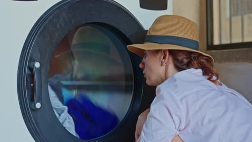 Woman Watching Clothes Tumble in Washing Machine