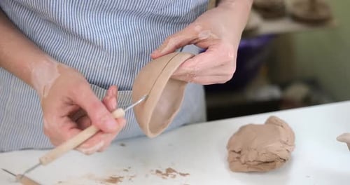 Woman Creates Pattern on a Clay Pot By Hands in Artistic Studio