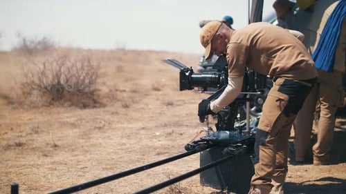 Man Adjusting Professional Camera on Set in Field