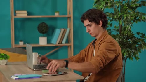 Medium Shot Capturing a Man Working on a Laptop in His Home Office Young Businessman is Getting a