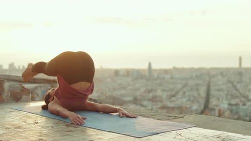 Woman Doing Yoga on Rooftop at Sunrise