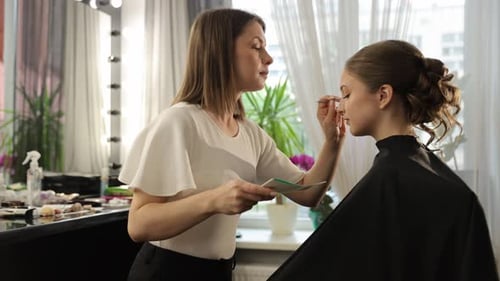 Woman applying makeup to client in beauty salon