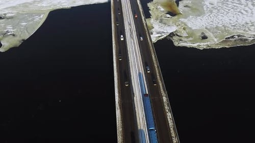 Luftaufnahme: Autobewegung auf der Autobahnbrücke über den gefrorenen Fluss im Winter