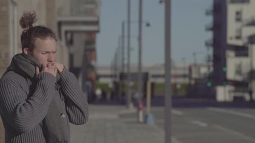 Man taking a deep breath on the street of an urban city. Person standing outside.
