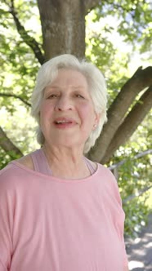 Vertical video portrait of happy senior caucasian woman with white hair in sunny nature, slow motion