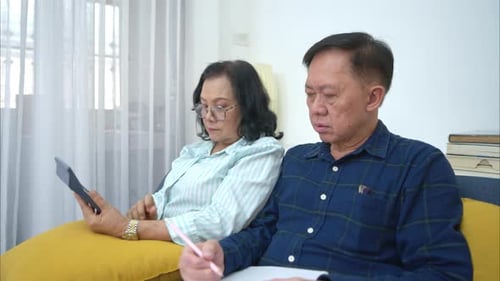 On a holiday, an elderly couple is relaxing at home, keeping a record of household