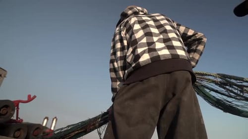 Fischer rollt sein Fischernetz nach einem frühen Morgen des Fischens im Meer. Fangtechnik in