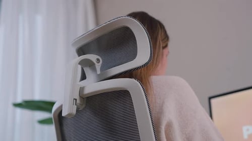 Rear Side View Of A Woman Seated In An Office Chair Working From Home. low angle, medium shot
