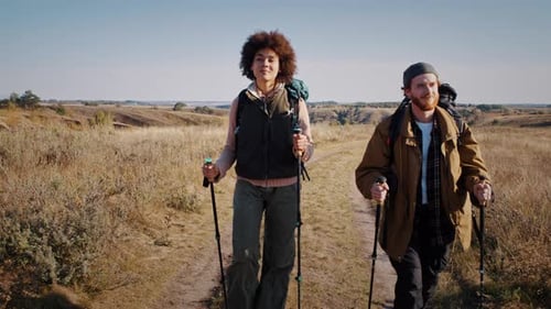 Hikers Trekking Across Grassy Hill with Hiking Poles