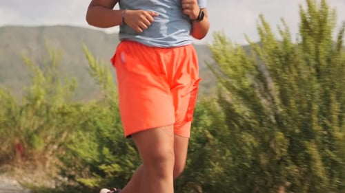 Overweight Girl Runs on a Mountain Road Pushing Through Fatigue Under the Sun