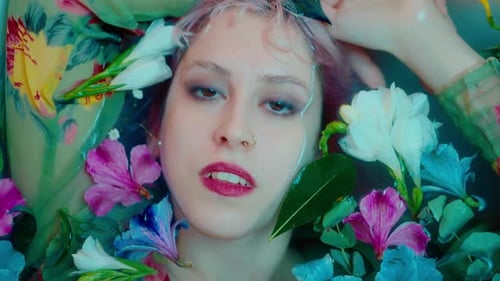 Woman Surrounded by Flowers Lying in Water