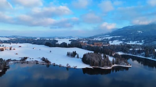 Calm river that hasn't frozen in winter. Drone footage approaching the snow-covered banks